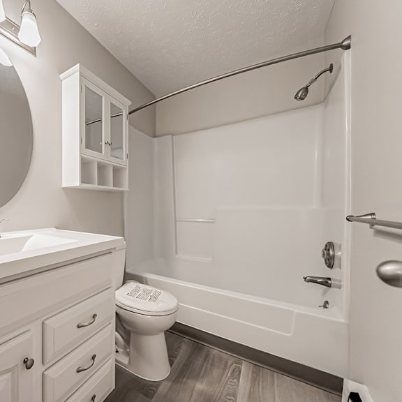 a white bathroom with a toilet, sink, and shower.