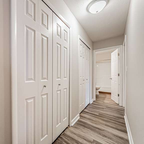 a hallway with white doors and wooden floors.