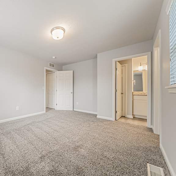 townhome upstairs bedroom, carpeted, with attached bathroom.