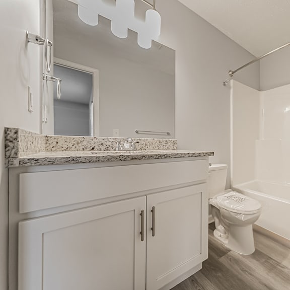 updated townhome bathroom with granite countertop and white tub.