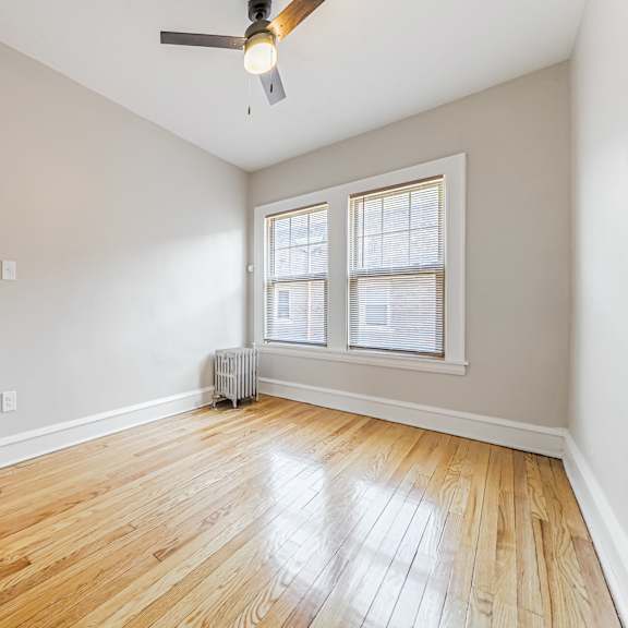 a room with a white door, a window with blinds, and a ceiling fan.
