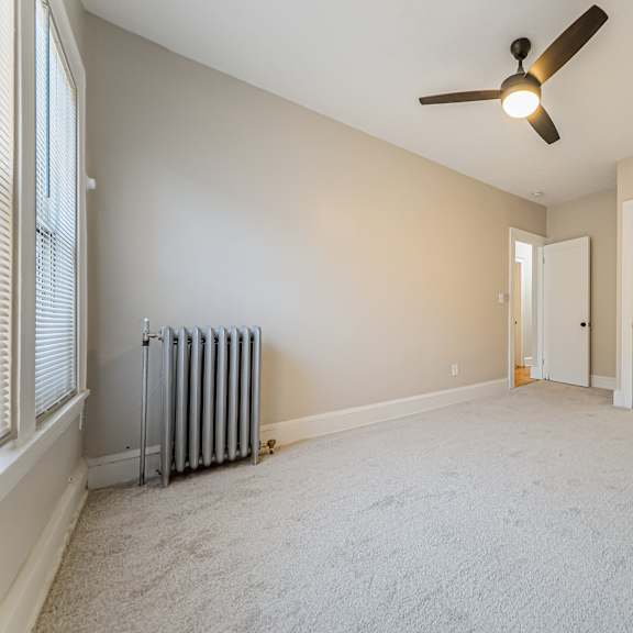 carpeted bedroom with large closet and a ceiling fan.