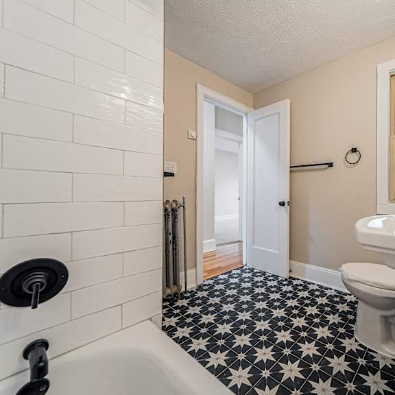 a white sink with a black faucet in a bathroom.