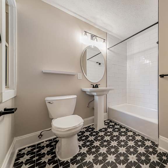 a bathroom with a toilet, sink, and a clock on the wall.