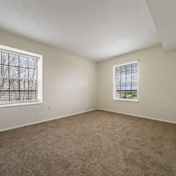 a bedroom with a large bed and a chair. at hunt club apartments, copley, oh, 44321