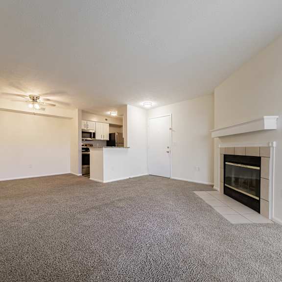 a spacious living room with a fireplace and a ceiling fan at hunt club apartments, copley