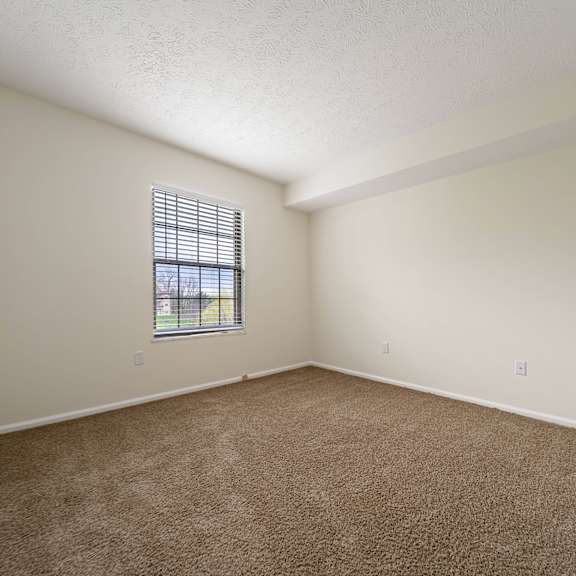 a room with a carpeted floor and a window with blinds at hunt club apartments, copley, ohio
