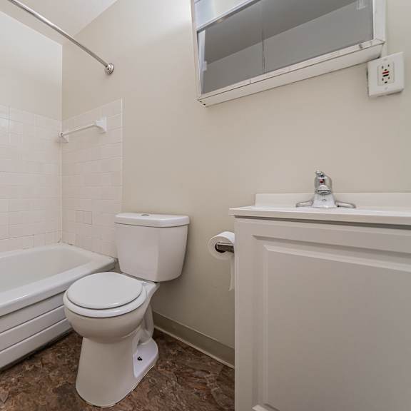 a white toilet sits next to a bathtub in a bathroom. at integrity berea apartments, ohio, 44017