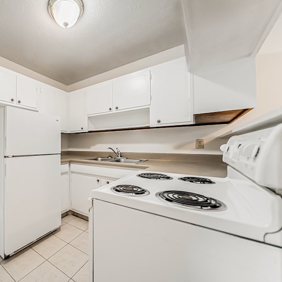 a white kitchen with a stove and a refrigerator.