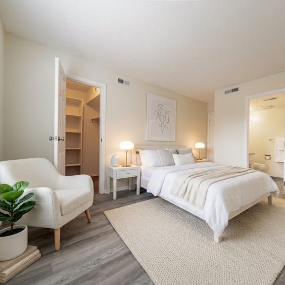 a bedroom with a large bed, a chair, and a potted plant at hunt club apartments, copley