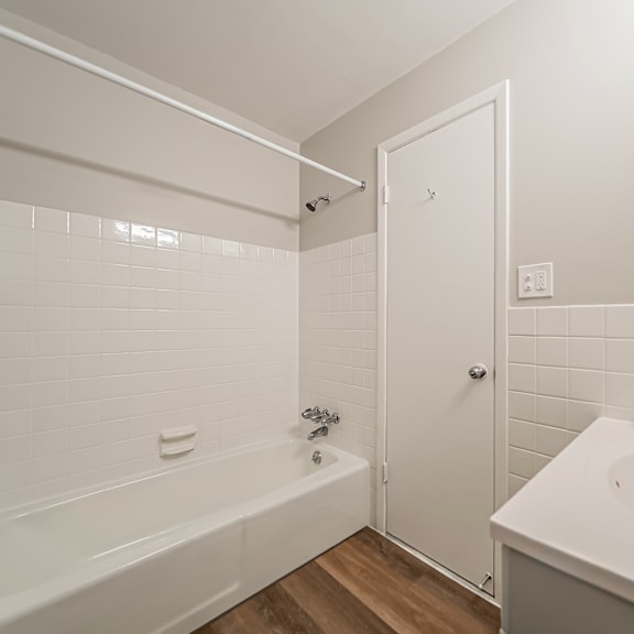 a white bathroom with a tub, sink and mirror.