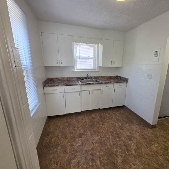 a kitchen with white cabinets and a brown floor.