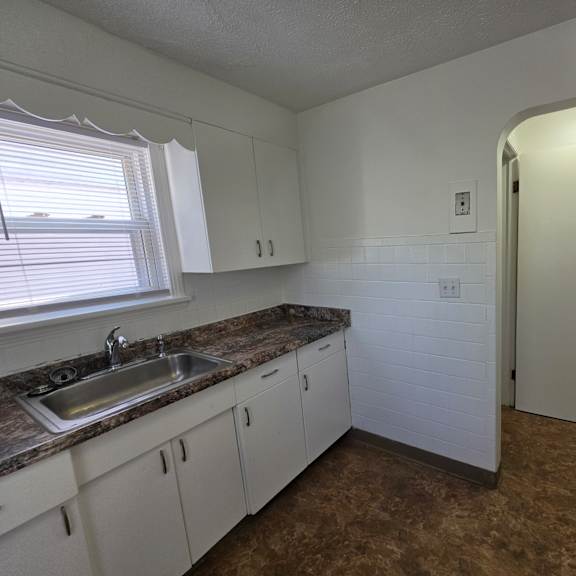 a kitchen with white cabinets and a marble countertop.