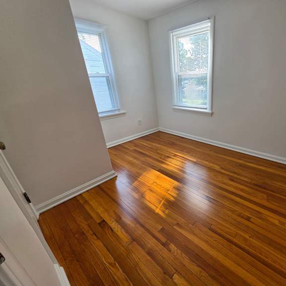a room with wooden flooring and two windows.