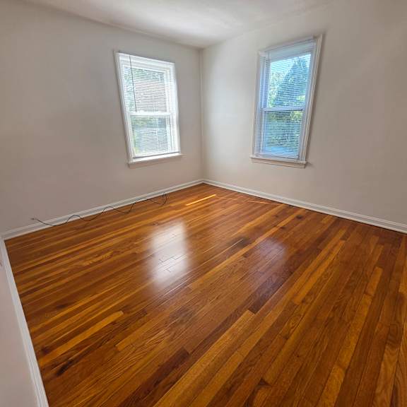 a room with wooden flooring and two windows.