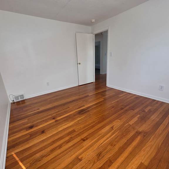 a room with wooden flooring and a white door.