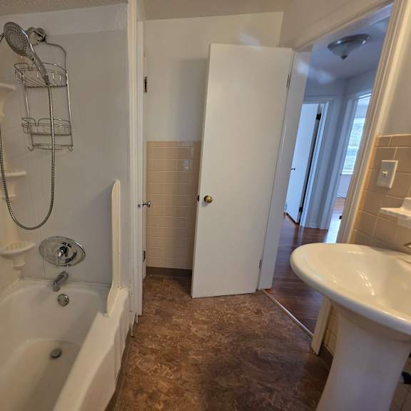 a white bathtub with a shower head and a shower hose.