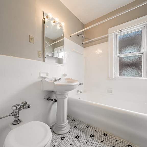 a white sink and toilet in a bathroom with a window at heights collection apartments, cleveland heights 44106