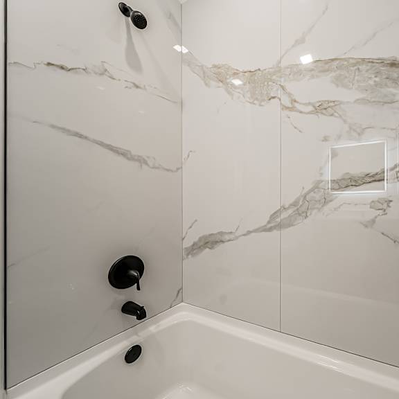 a white bathroom with a marble patterned shower at westwood meadows, westlake, oh, 44145