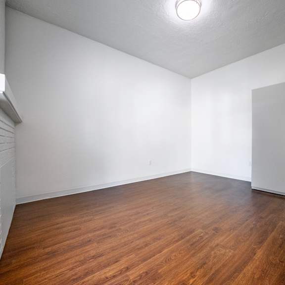 a bedroom with wooden floors and white walls.