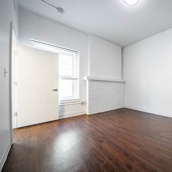 a bedroom with wooden floors and white walls.