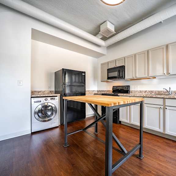 a kitchen with black appliances and wooden floors.