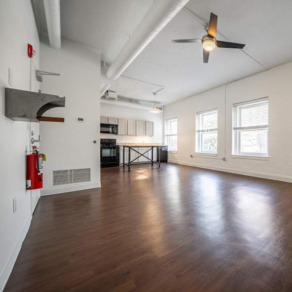 a large living room with a ceiling fan and wooden flooring.