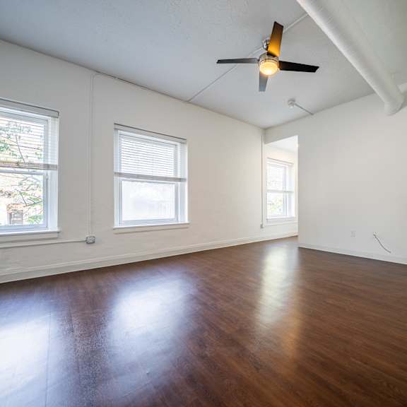 a room with a ceiling fan and wooden flooring.