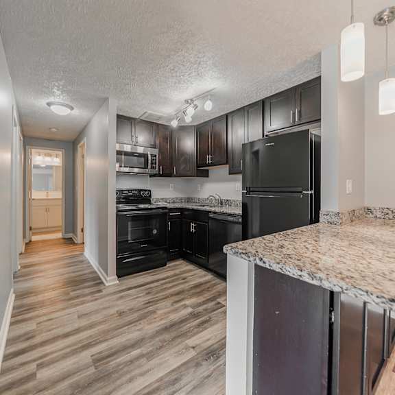a kitchen with black appliances and wooden floors. at integrity berea apartments, berea, 44017
