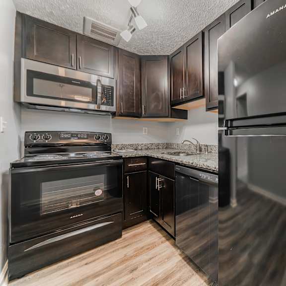 a kitchen with black cabinets and a stainless steel refrigerator. at integrity berea apartments, apartments, berea, oh
