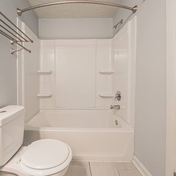 a white toilet sits next to a white bathtub in a bathroom. at integrity berea apartments, berea, 44017