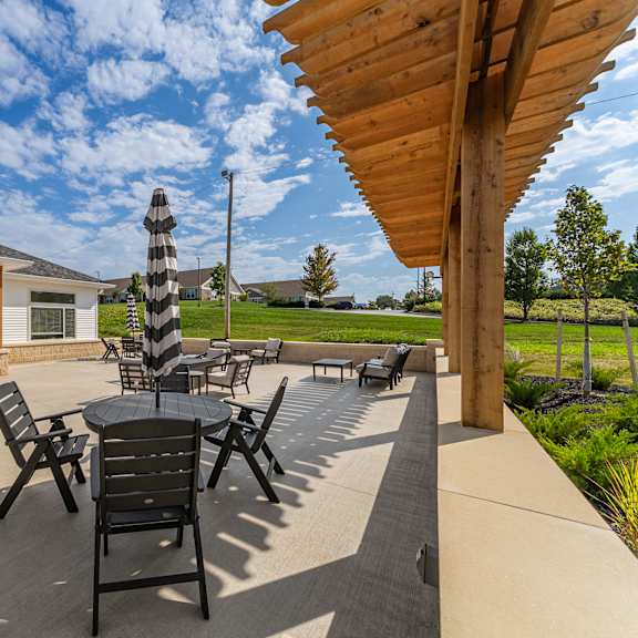 a patio with a table and chairs is shaded by a wooden pergola..