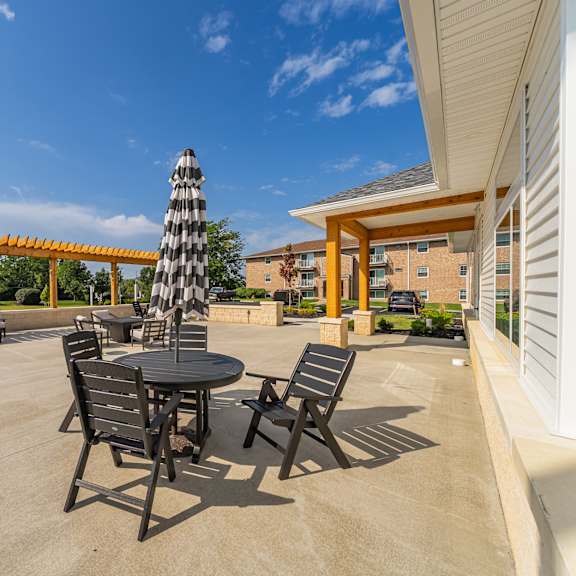 a patio with a table and chairs and a striped umbrella..
