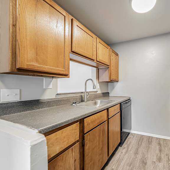 a kitchen with wooden cabinets and a black refrigerator at integrity chardon apartments,ohio
