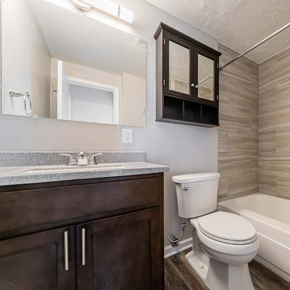 a bathroom with a white toilet, a sink, and a bathtub at integrity chardon apartments, chardon