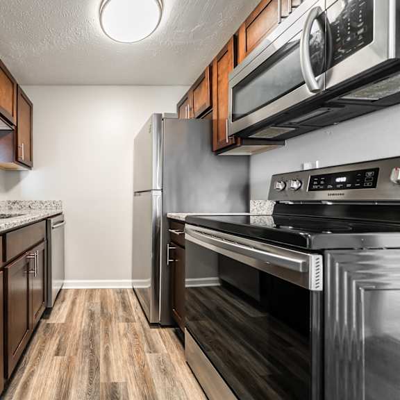 a kitchen with dark wood cabinets and stainless steel appliances at integrity chardon apartments, oh, 44024
