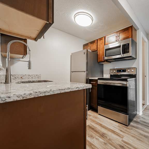 a kitchen with a granite countertop and wooden cabinets at integrity chardon apartments,ohio, 44024
