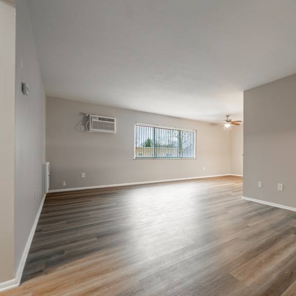 a room with wooden flooring and a window with blinds.