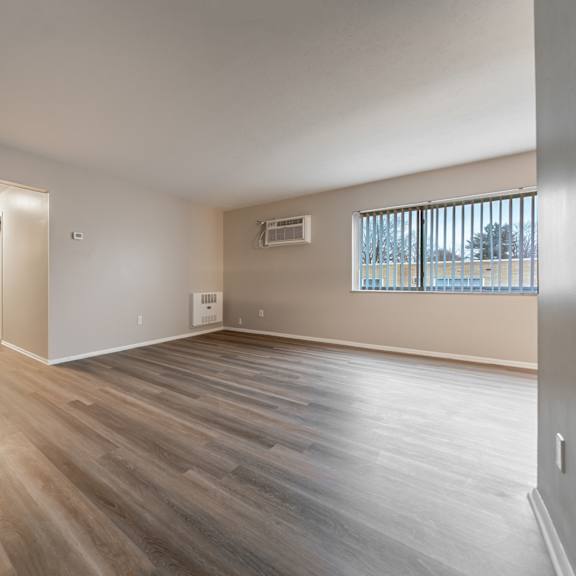 a room with wooden flooring and a window with blinds.
