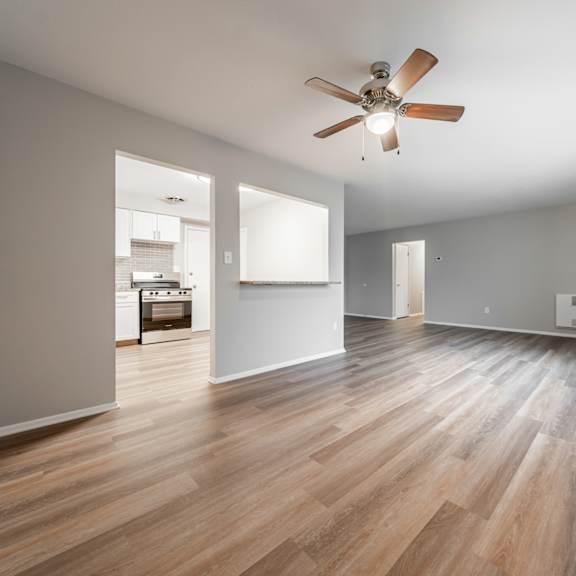 a room with a ceiling fan and wooden flooring.
