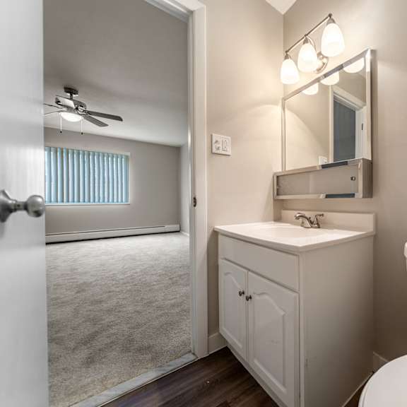 a bathroom with a toilet, sink, and mirror.