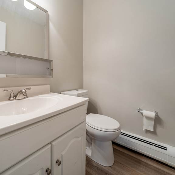 a white bathroom with a toilet, sink, and mirror.