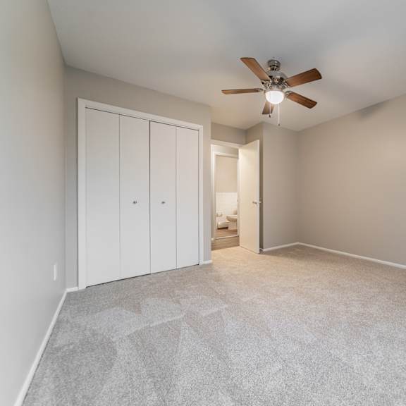 a room with a ceiling fan and carpeted floor.