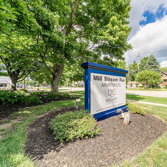 a sign for mill stream run apartments is shown in front of a tree.