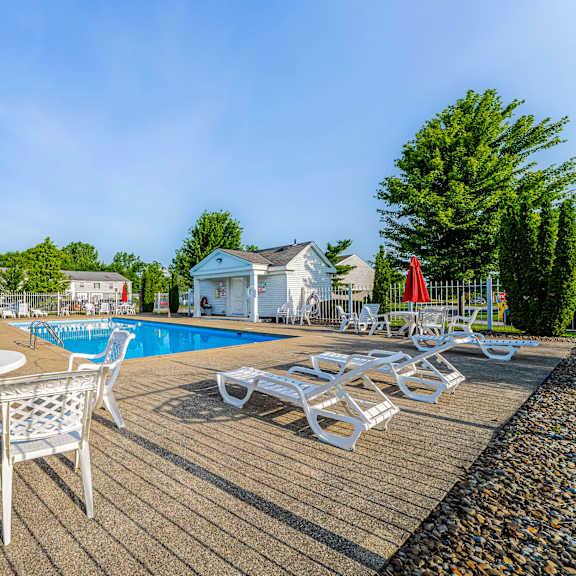 a poolside area with white chairs and a table.
