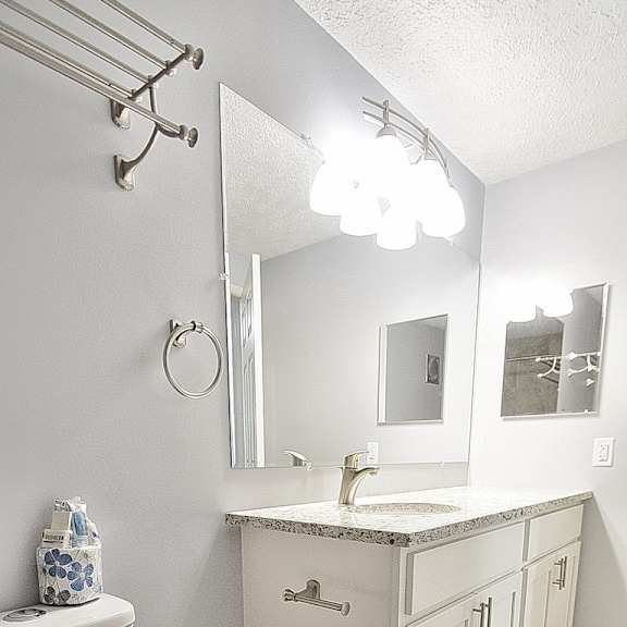 a white toilet with a white toilet paper holder and a white sink with a white cabinet.