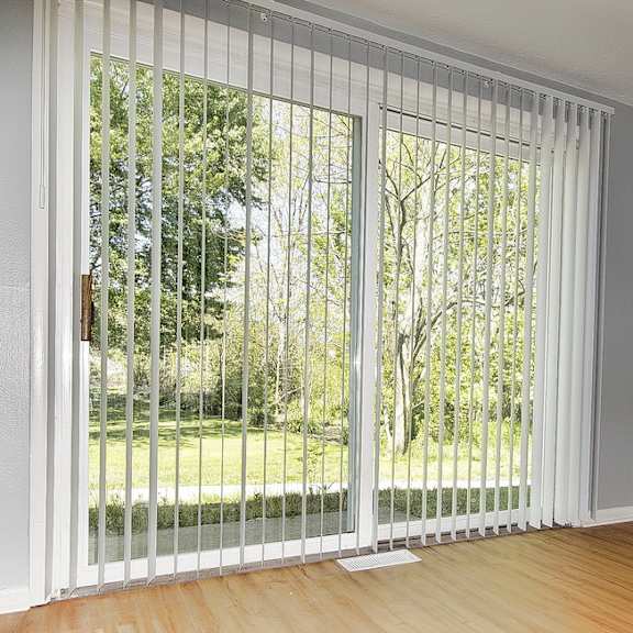 a room with a sliding glass door leading to a garden.