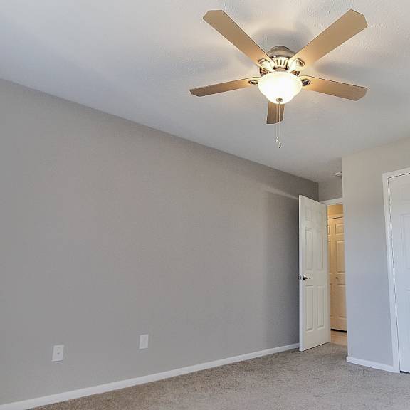 apartment bedroom with carpeting and a ceiling fan light.
