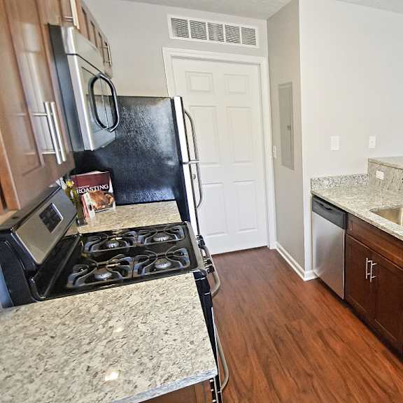 townhome galley kitchen with granite countertops and a dishwasher.