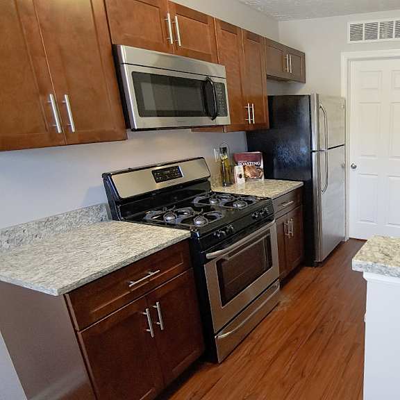 townhome kitchen peninsula with granite counters, stainless steel appliances, and hardwood flooring.